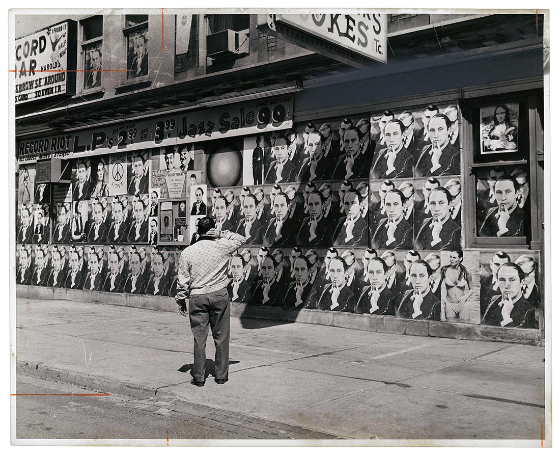 A man looks at a wall that is covered in photographs of Pierre Elliot Trudeau