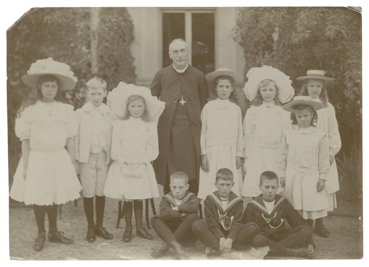Group of young children standing around the Bishop of London. Black and white photograph by Minna Keene.