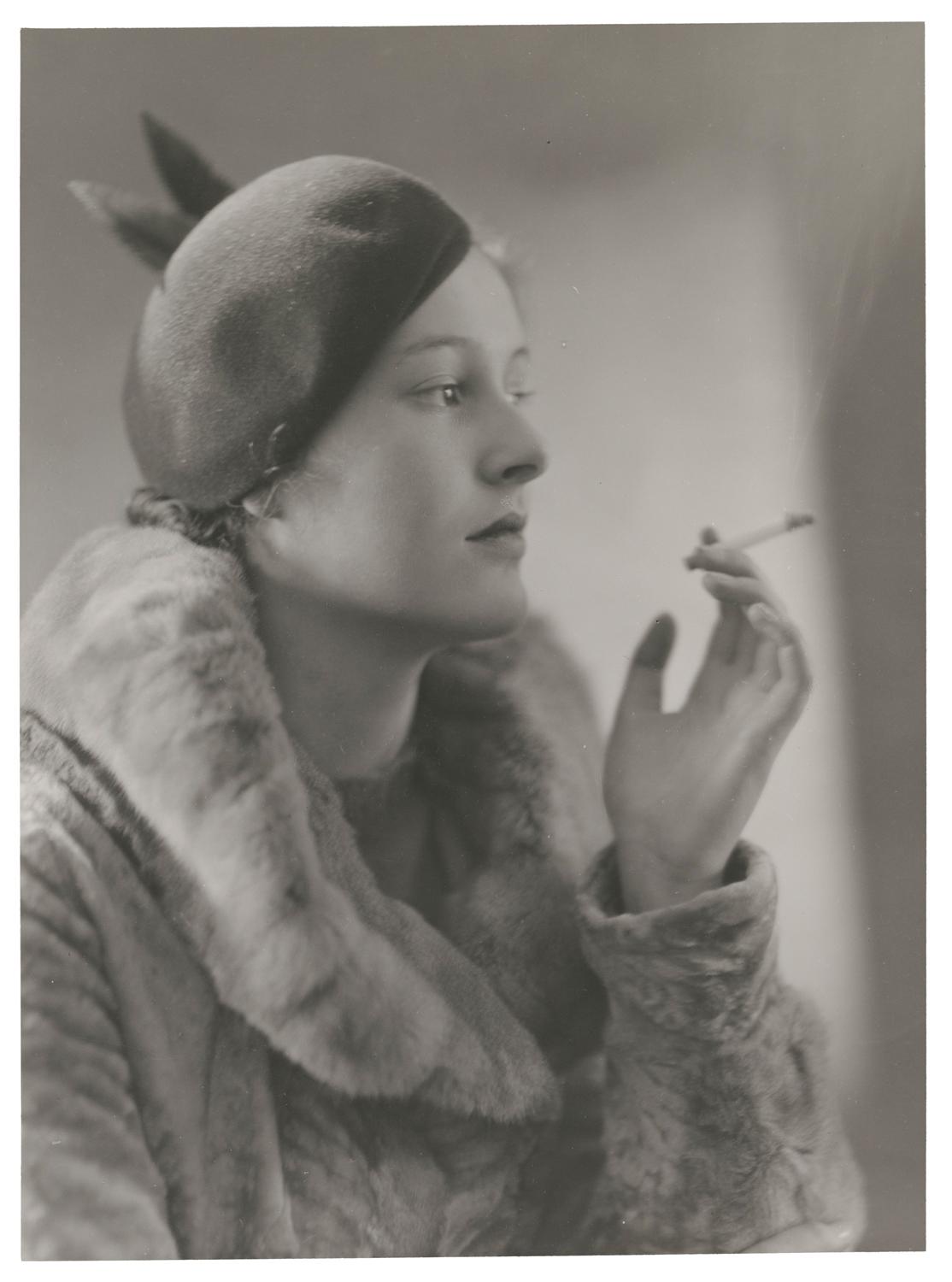 A profile of a woman in a fur coat holding a cigarette looking to the right. Black and white photograph by Violet Keene Perinchief