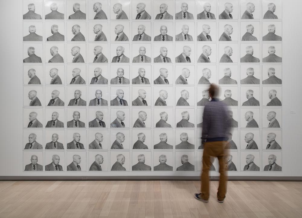 A man examines a wall full of black and white photographs