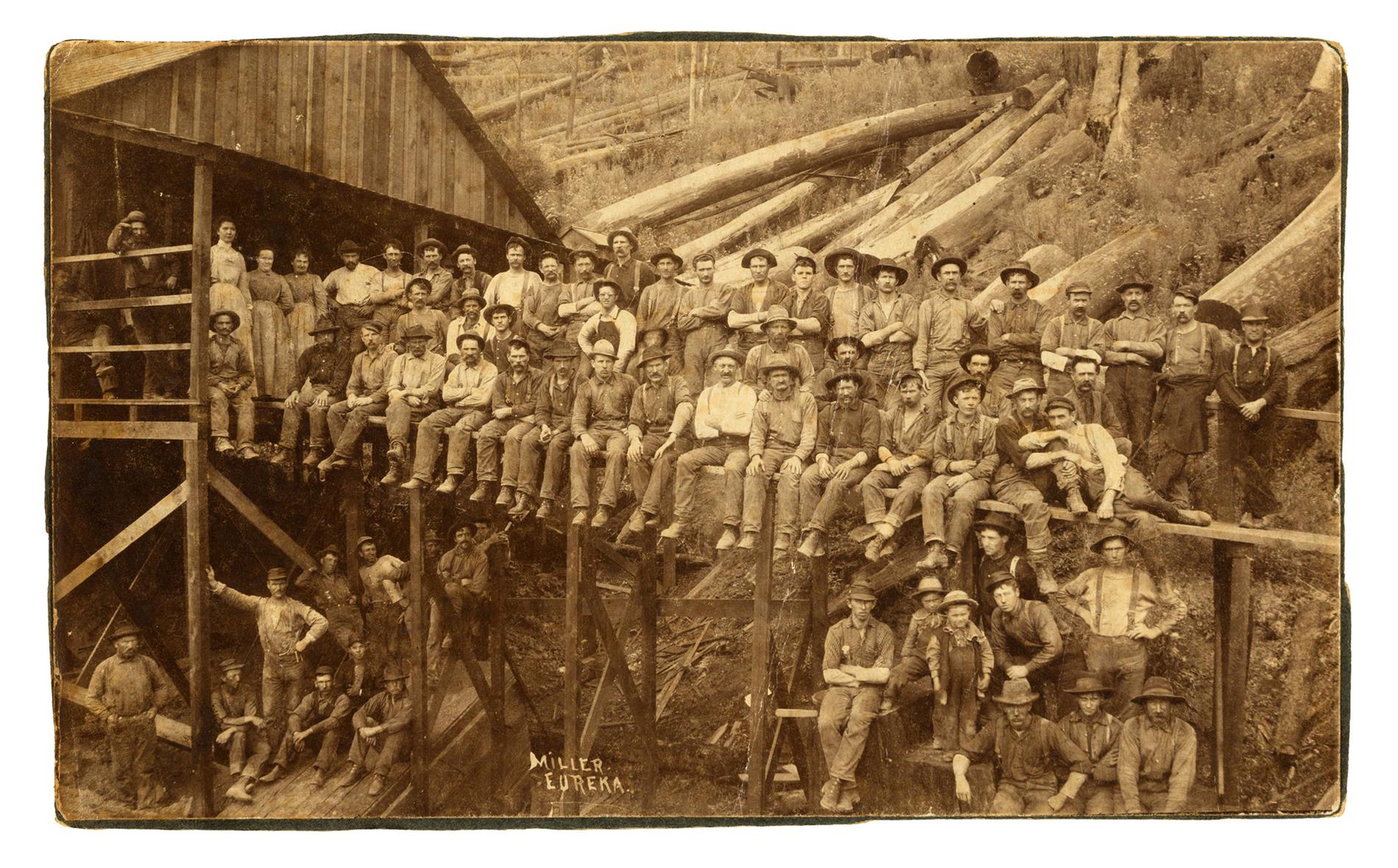 A large group photo of workers on a wooden platform