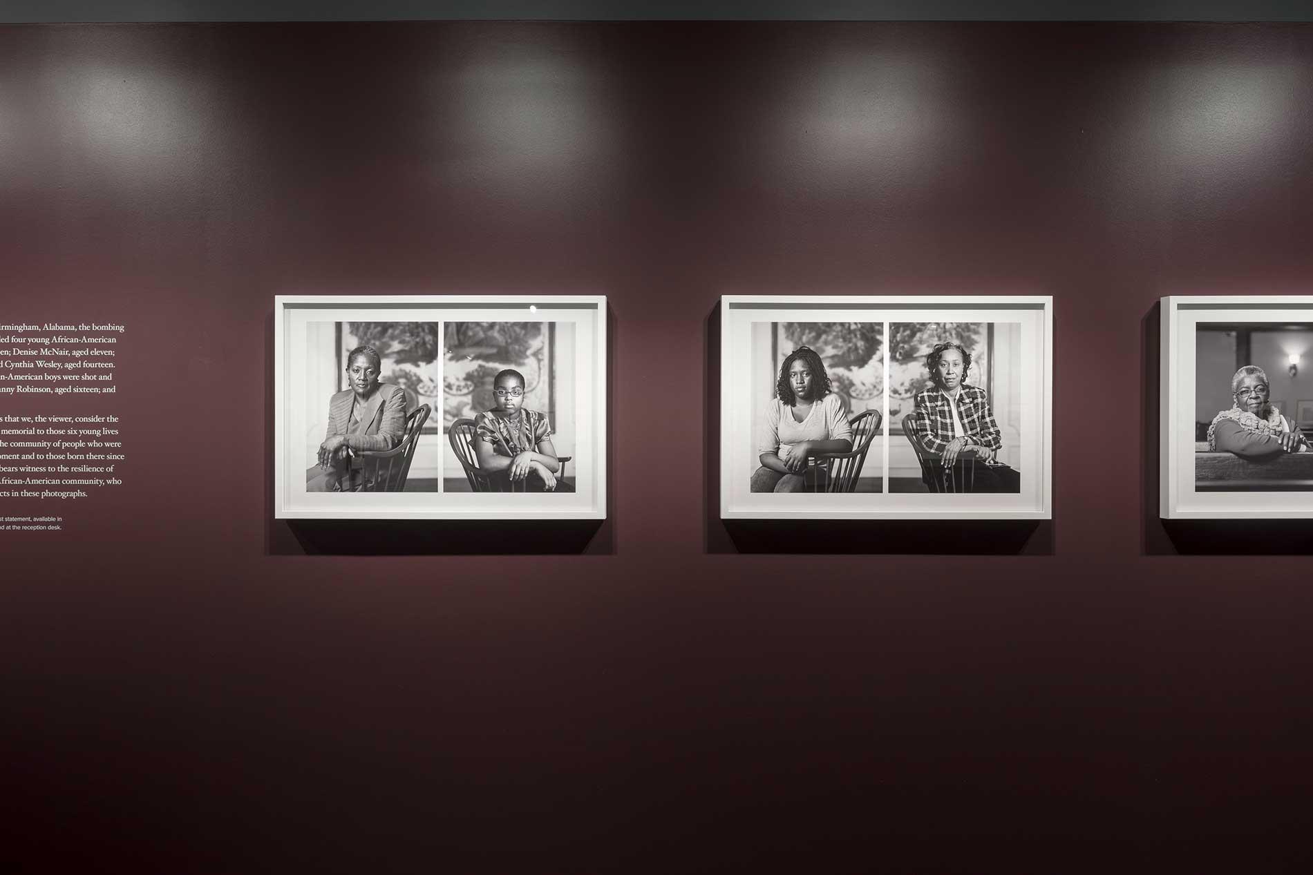 Photographs in white frames hanging on a burgundy gallery wall
