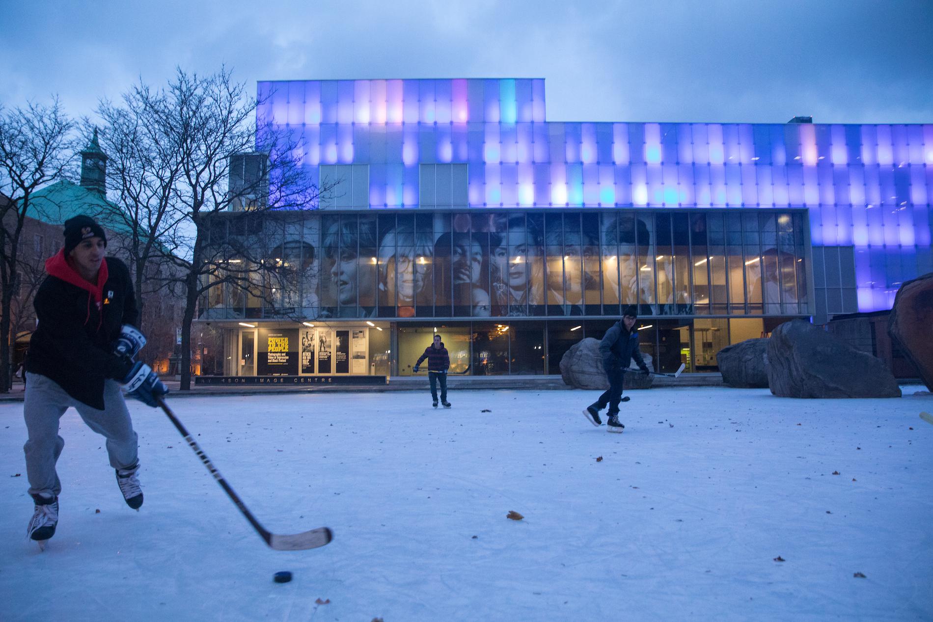 A group of boys play hockey outside the Ryerson Image Centre