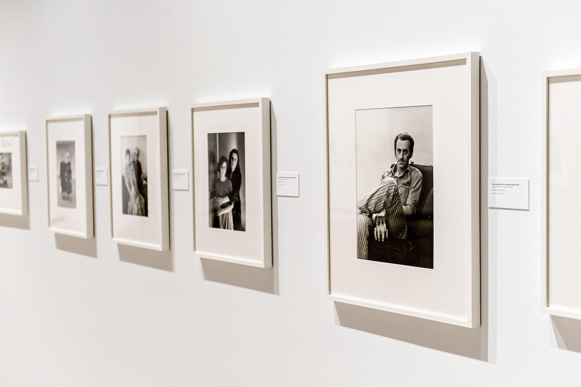Black and white photographs in white frames, evenly spaced on a white wall