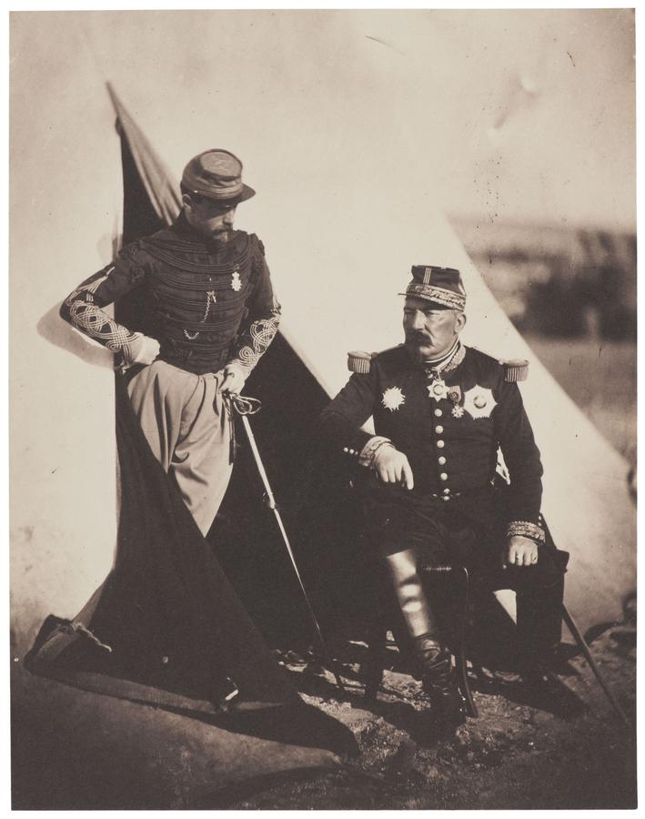 Two soldiers outside a tipi, one stands in the doorway, the other sits