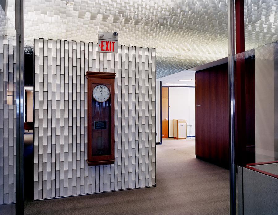 An empty office with a grandfather clock mounted on a textured wall