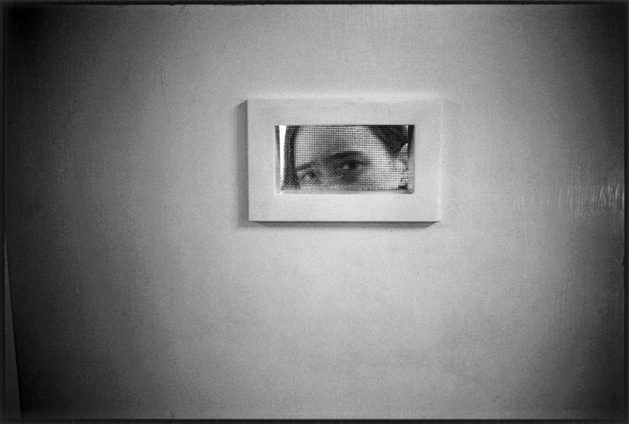 A woman peeks out of a small window in a doorway. Photograph by Mary Ellen Mark.