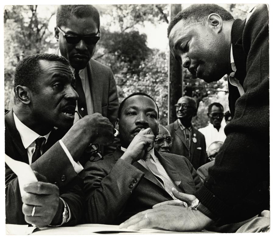 Dr Martin Luther King Junior sits with a group of men wearing suits