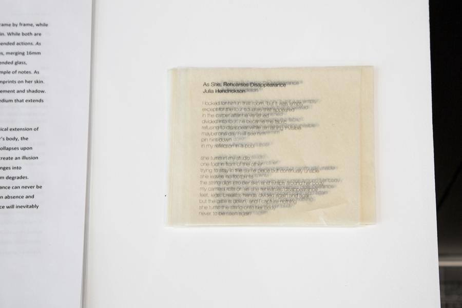 Blurry text printed on layers of paper. Title reads "As she, rehearses disappearance, Julia Hendrickson"