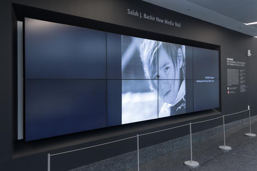 Screen displaying a young child's face. Text on the wall reads 'Salah J. Bachir New Media Wall.'