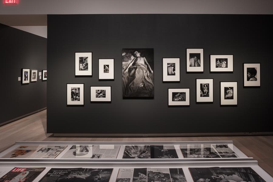 A gallery with photographs adorning its dark grey walls, and a vitrine in the forefront