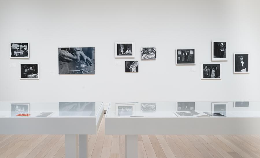 Black and white photographs on the wall behind two white display cases