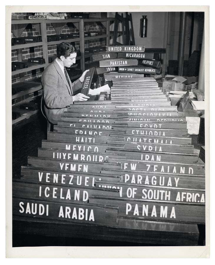 A man sorts through country desk plates in preparation for the United Nations General Assembly in 1949.