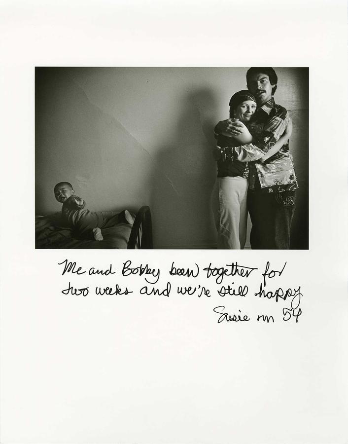 A photo of a couple with a young baby on the bed, and writing on top of the photo