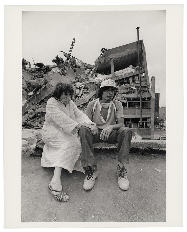 Two people sitting in front of a pile of rubble