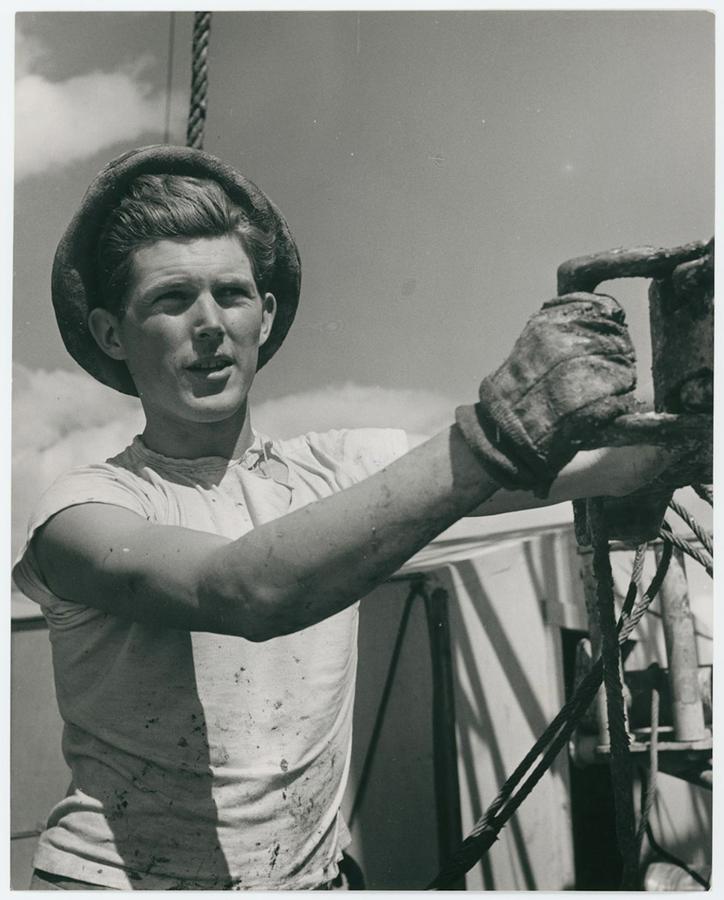 A young oil worker wearing a dirty white tshirt and work gloves