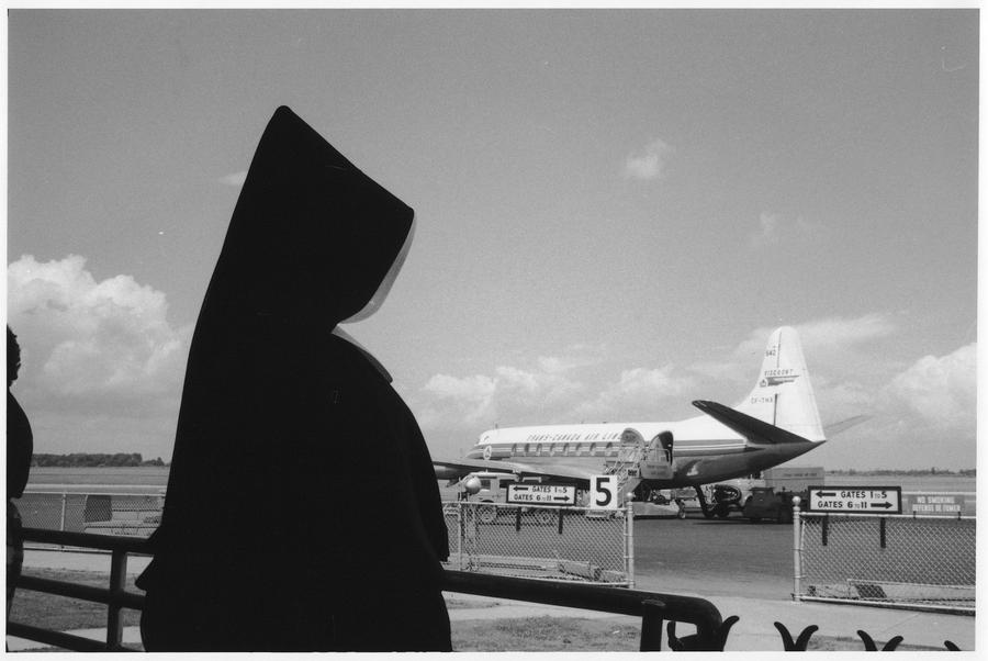 A nun in a black habit looking out at the airport tarmac