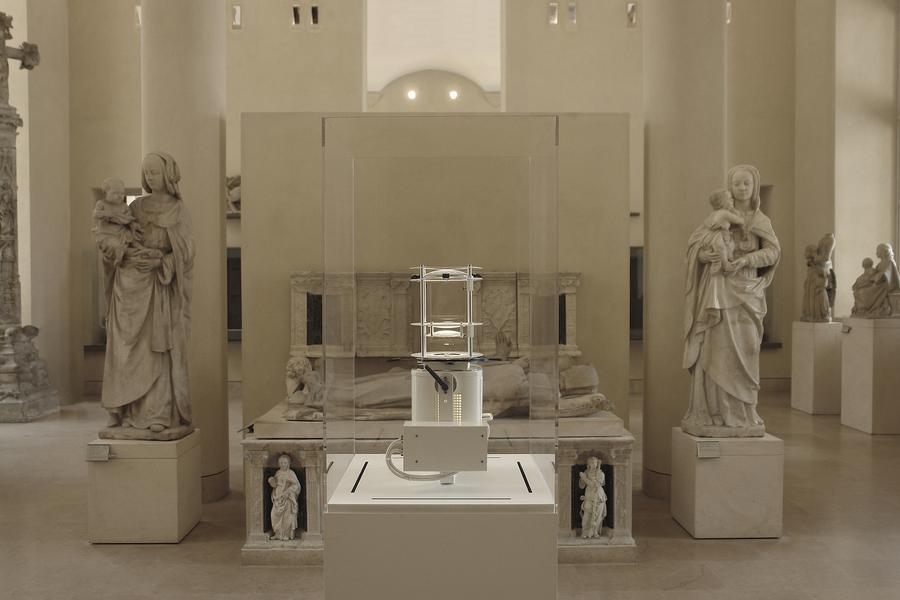 A glass display case in front of marble statues and sculptures