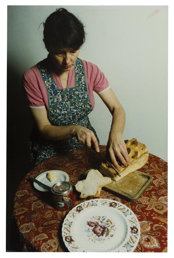 Photo of woman slicing bread at a table.