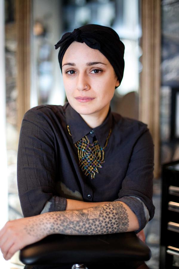 A portrait of a girl with tattoos and a head scarf