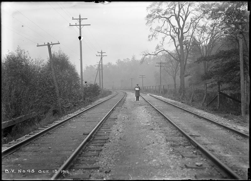 A lone person walking in between train tracks