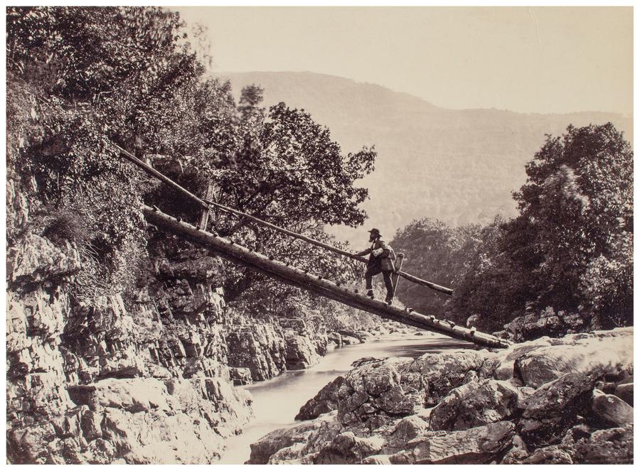Black and white photograph showing a man walking up a steep wooden bridge. Photograph by Francis Bedford.
