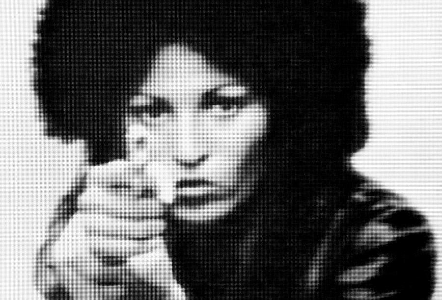 A woman with an afro points a hand gun