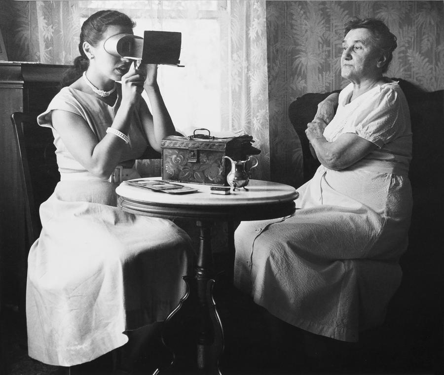 Two women at a small table, one looking through a viewfinder