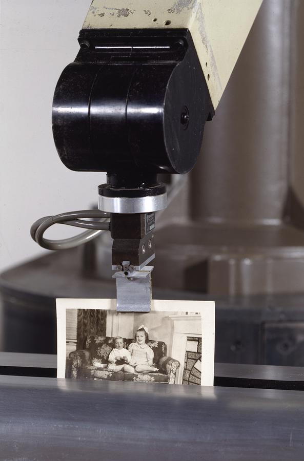 A machine holds a sepia tone vintage photograph