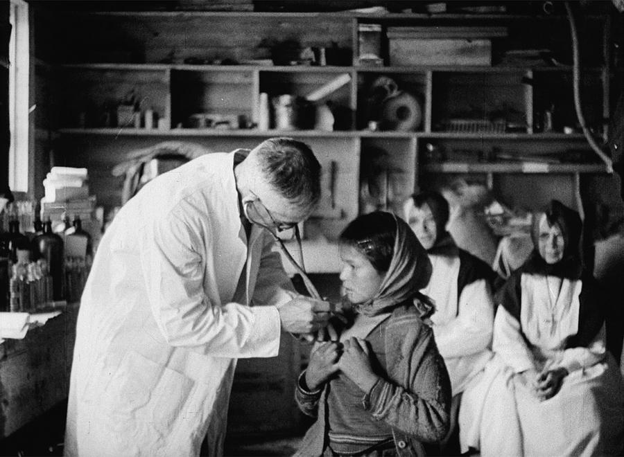 A white doctor checks the heartbeat of a young Inuit girl