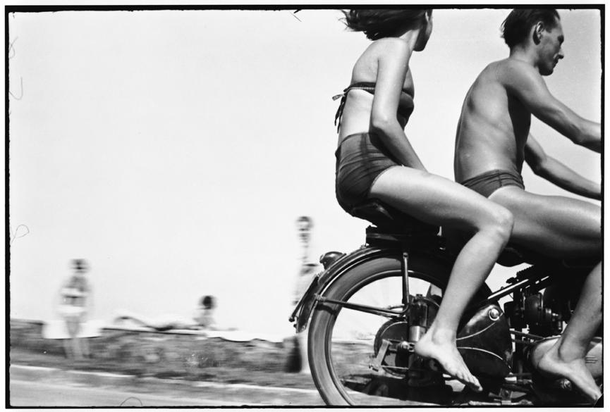 A couple rides a motorbike in swimsuits