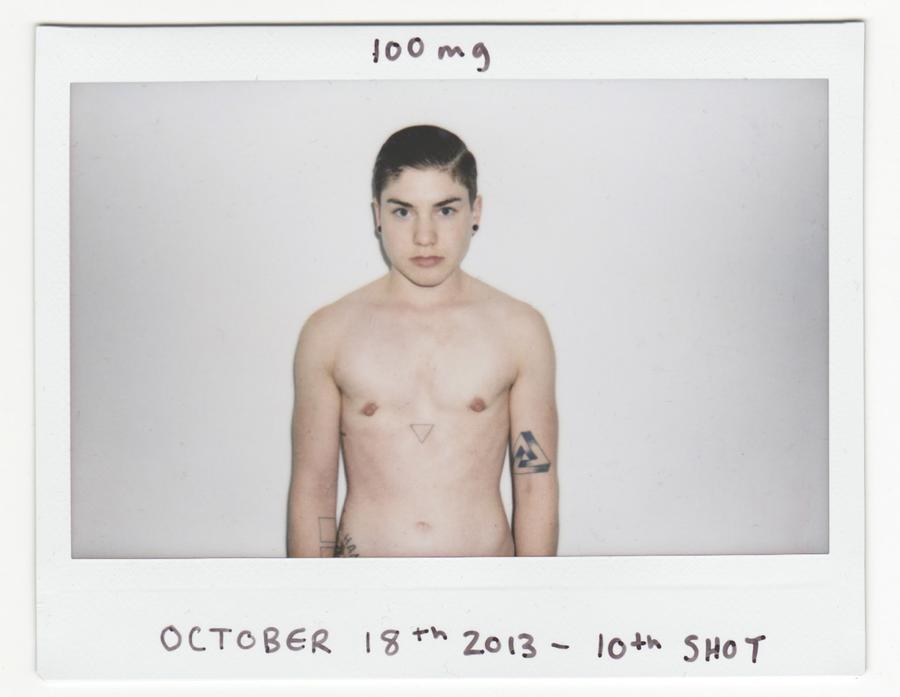 A shirtless man in front of a white wall staring at the camera. The handwritten text reads "100 mg. October 18 2013. 10th shot."