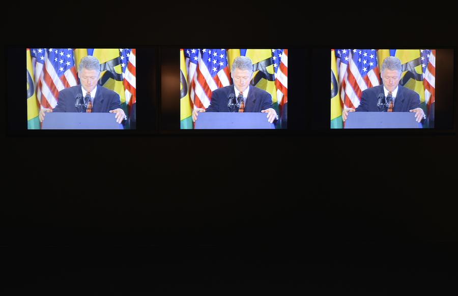 Three identical screens show Bill Clinton standing at a podium in front of American flags