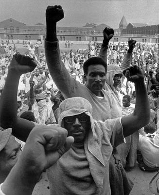 Two men raising their fists in the air, hundreds of other men in the background are doing the same