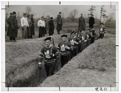 Members of the Toronto Maple Leaf hockey team wearing their hockey jerseys while training for the war in a trench