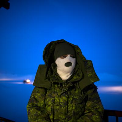 A portrait of a person in a white balaclava and a camo jacket.